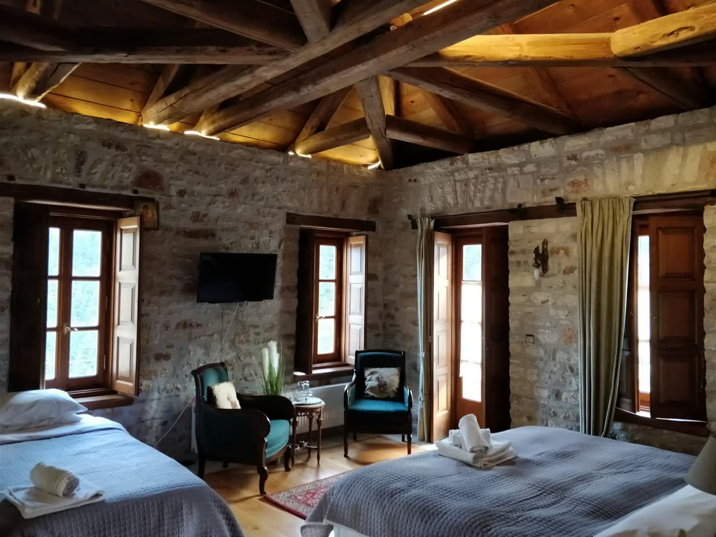 A bedroom with stone walls and two made beds