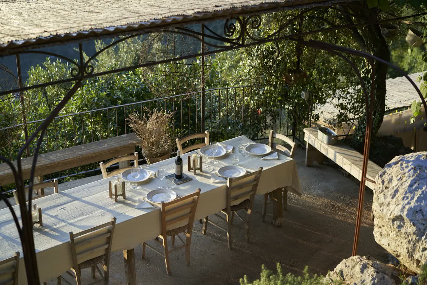 A long table laid on a terrace under a pergola